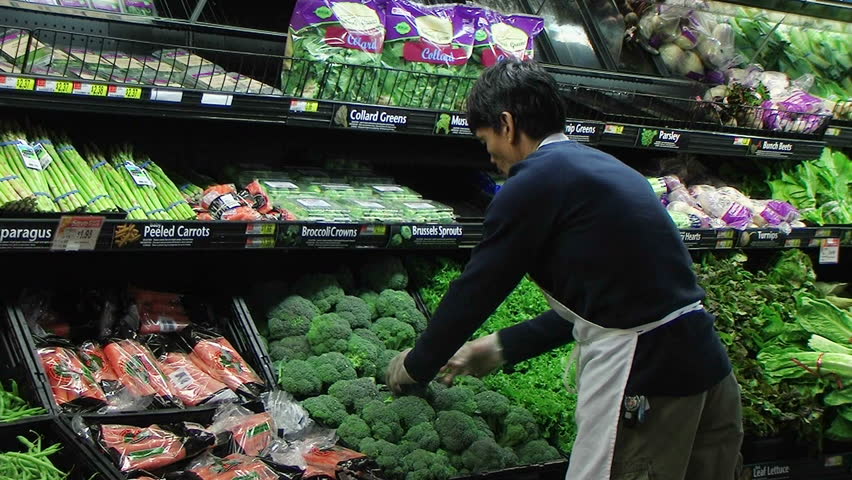 Worker Facing Produce Display Of Fresh Broccoli In Grocery Store. Stock 