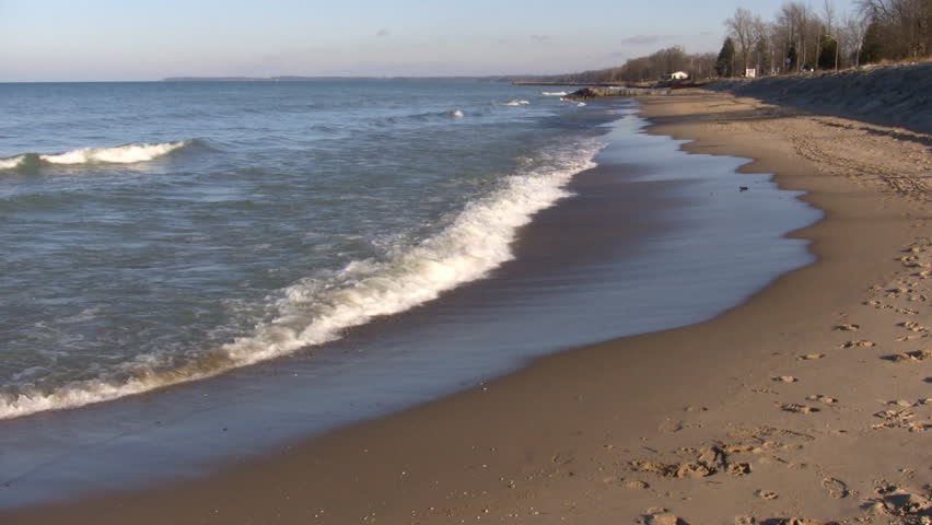 Waves Gently Hit The Beach Then Recede As The Sunlight Illuminates The 