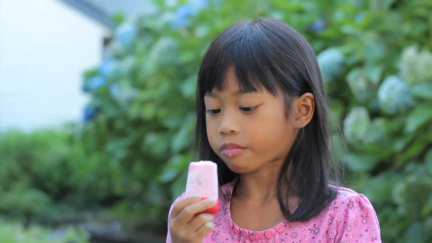 A Cute Little 6 Year Old Asian Girl Enjoys A Delicious Pop
